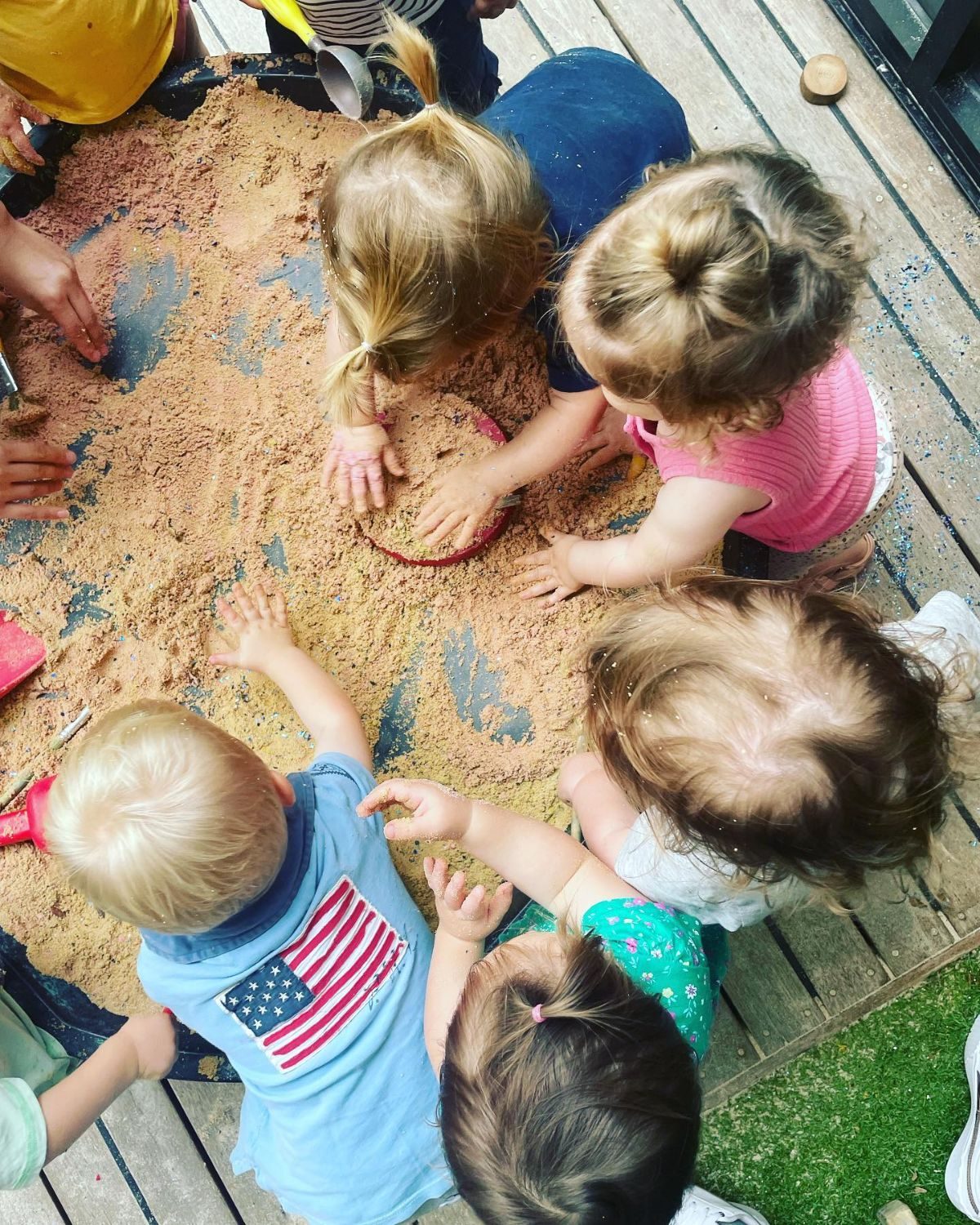 Preschool children working together in a large sand tray