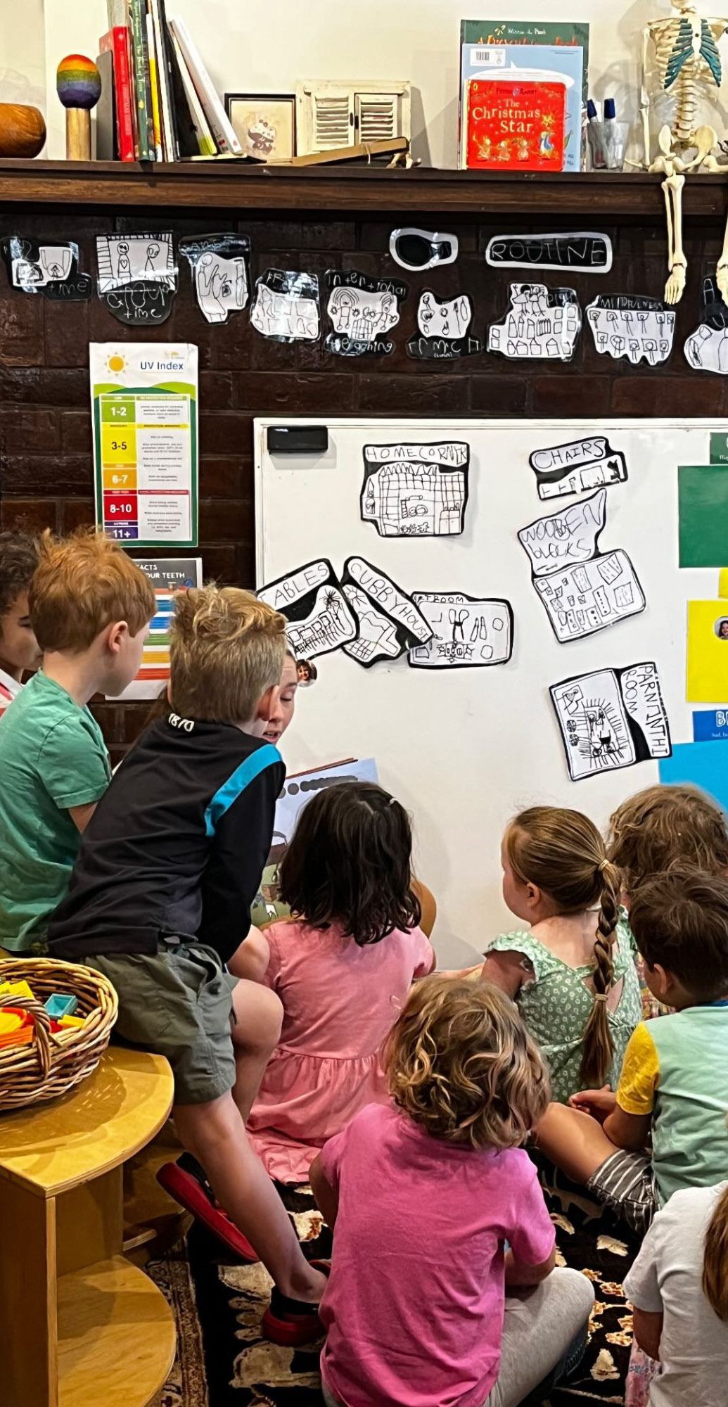 Toddlers gathered together at group time, looking at a picture book